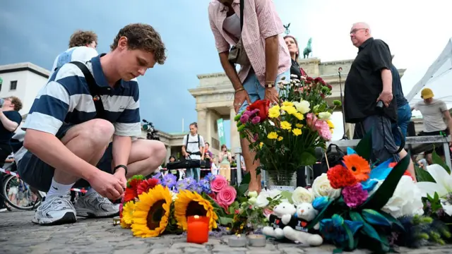 A person kneeling down in front of flowers on the floor