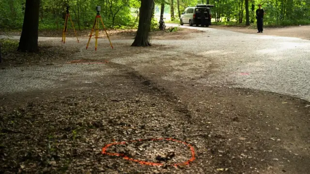 An orange circle is drawn on the floor in Tiergarten park. A curved tyre track can be seen next to the marking