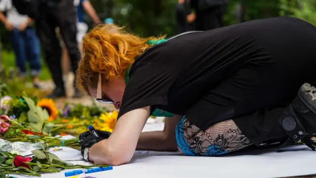A person leaves a message next to flowers near the scene of the attack
