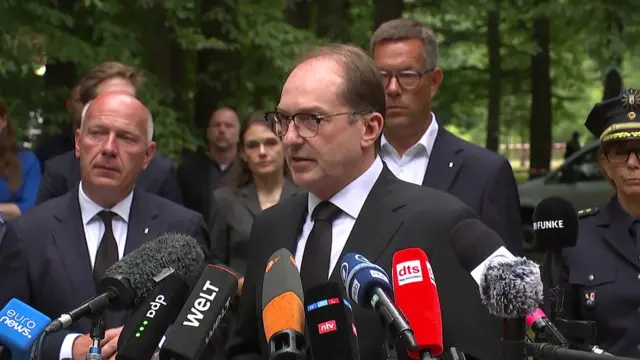 Alexander Dobrindt stands in front of a range of microphones as he speaks
