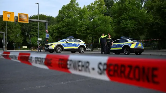 Two police vehicles are seen behind police tape