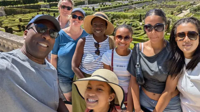 A group of eight people pose for a photo with the grounds of Chateau Villandry behind them
