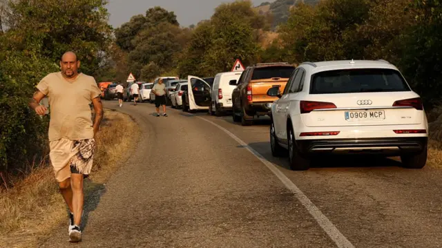 A man runs along a road next to a line of traffic