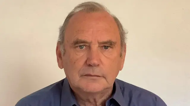 John Kay is pictured looking at the camera, wearing a blue shirt.