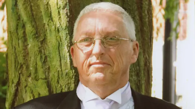 Man dressed for a wedding stood in front of a tree