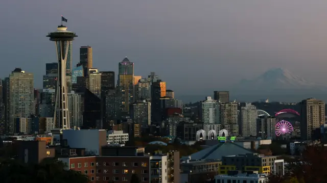 The Seattle cityscape is seen, with a snowy mountain peak in the background.