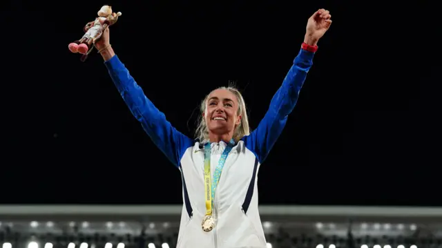 Eilish McColgan holding his hands up in the air with her gold medal around her neck at the Commonwealth Games in Birmingham 2022