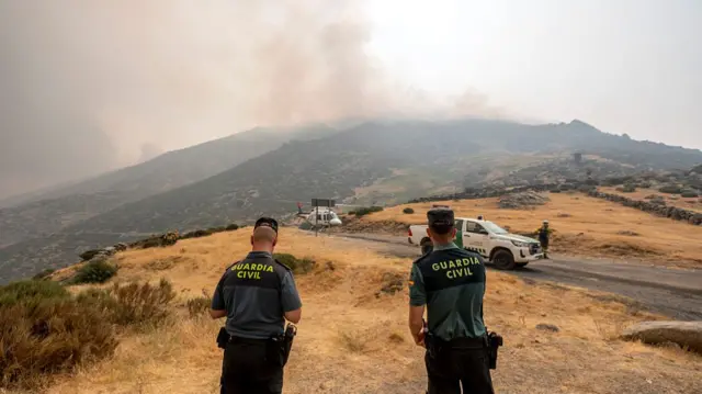 Two guards watch a wildfire on a hillside in Spain