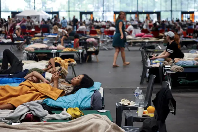 A woman looks at her phone on Saturday at the Bordeaux-Lac Exhibition Centre, which has been turned into a shelter for evacuated people