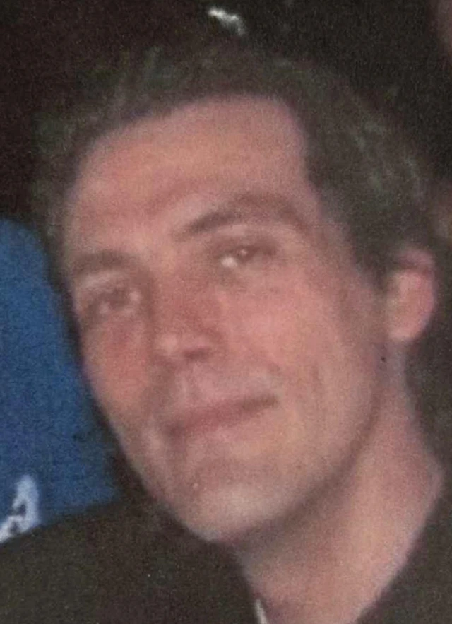 A man with brown hair smiles at the camera - the photo is blurry
