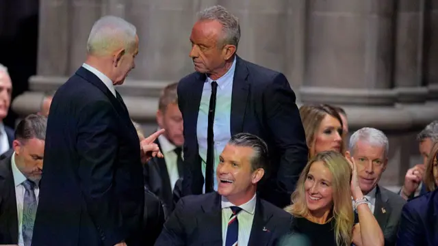 Hegseth smiling as he sits before Kennedy