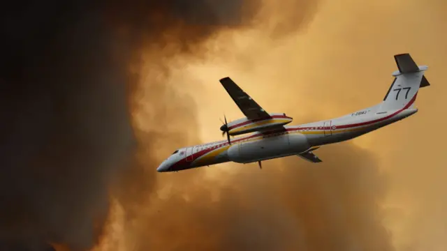 A propeller plane flying through orange and black smoke clouds