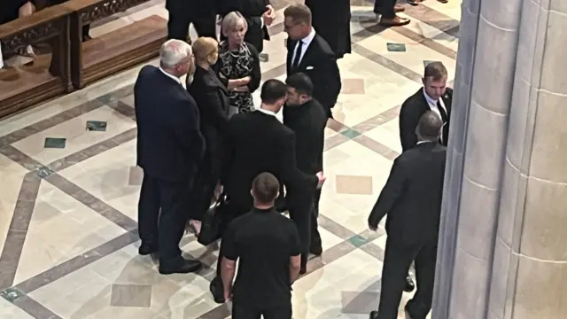 A group of people can be seen standing inside a cathedral. Among them is Ukrainian President Volodymyr Zelensky