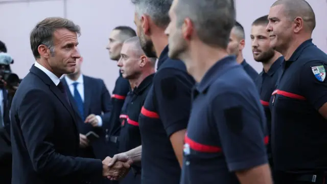 Macron shakes hand with a firefighter during a visit to the Gironde region