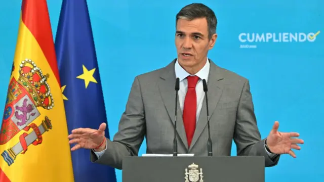 Pedro Sanchez, who has short dark hair, speaks at a podium while wearing a business suit