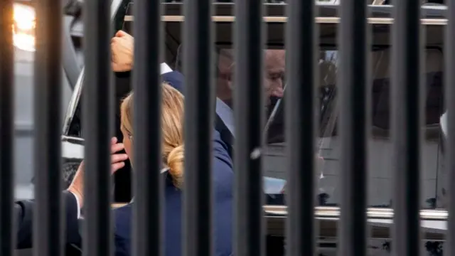 Netanyahu getting into a car, while a security agent holds it for him
