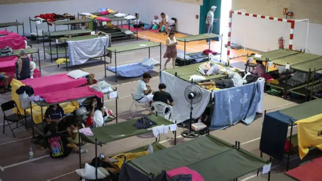 People sheltering in temporary accommodation in a sports hall