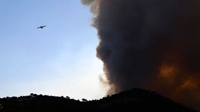 A firefighter airplane near Cebreros on Monday, alongside huge cloud of black smoke