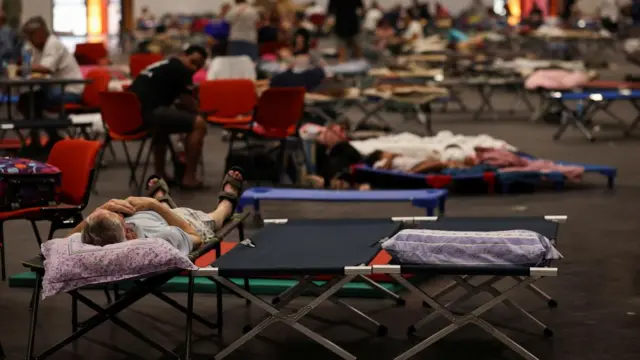 People lying on cots in an evacuation centre.