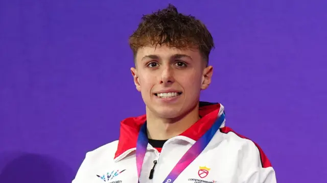Filip Nowacki smiles for the camera wearing his silver medal