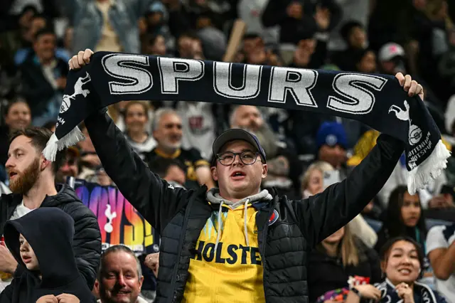 A supporter of Tottenham raises his scarf