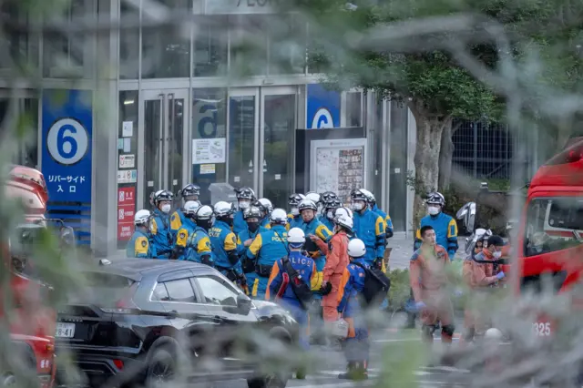 A large group of emergency workers in blue and yellow boiler suits.