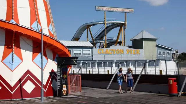 Clacton pier with a wooden boardwalk and a red and white helter skelter.