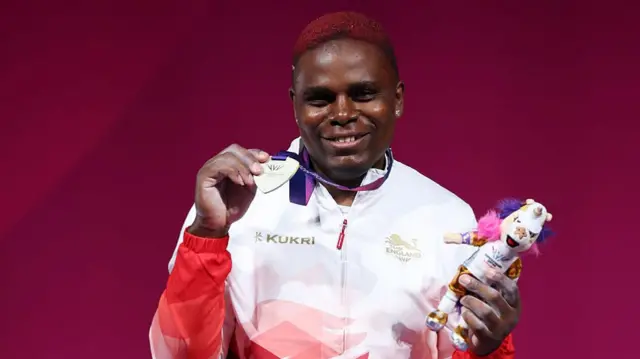 A smiling Madias Ngake shows her medal to the crowd