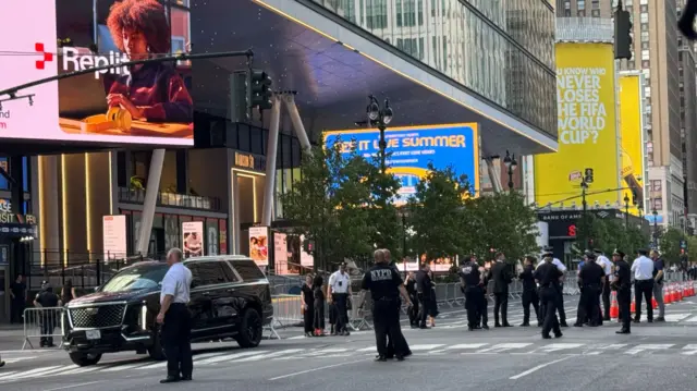 A line of police and security officers are seen in the road outside Madison Square Garden. A black car can be seen nearby