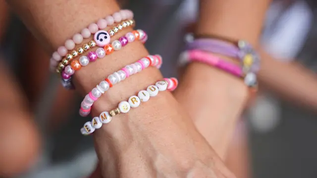 The wrist of a person with several bead bracelets on it, including one that reads Team Bride