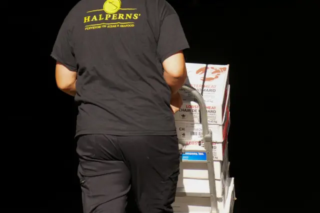 A worker pushes a trolley with boxes labelled 'lobster meat' on them