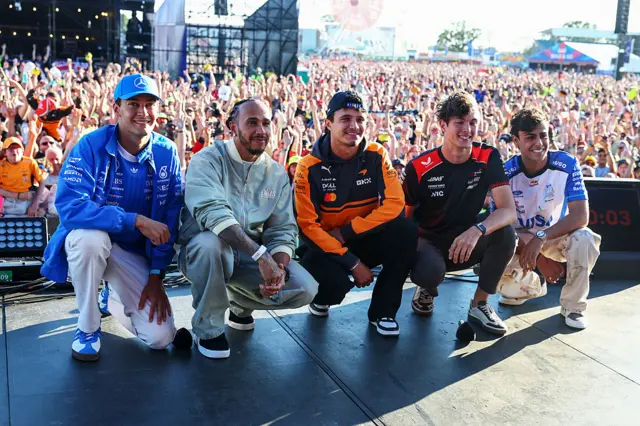 George Russell, Lewis Hamilton, Lando Norris, Ollie Bearman and Arvid Lindblad pose for a photo in fron of the fans at Silverstone
