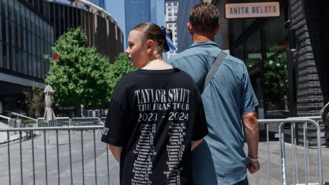 A person wears a Taylor Swift tour t-shirt outside MSG next to a man in a blue shirt