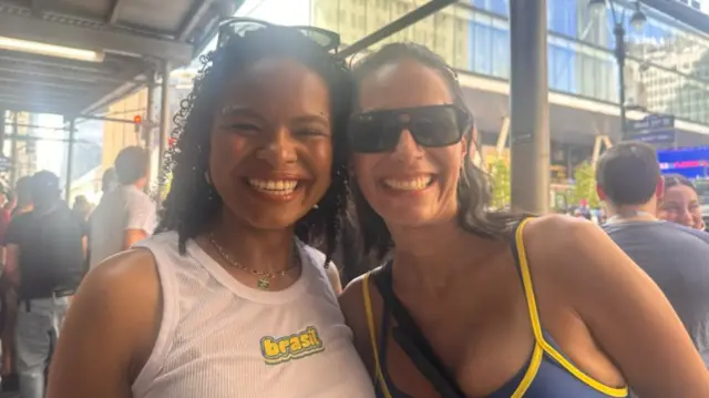 Two women wearing sleeveless tops smile at the camera