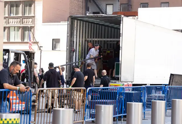 Men remove equipment from a large van behind fences outside Madison Square Garden