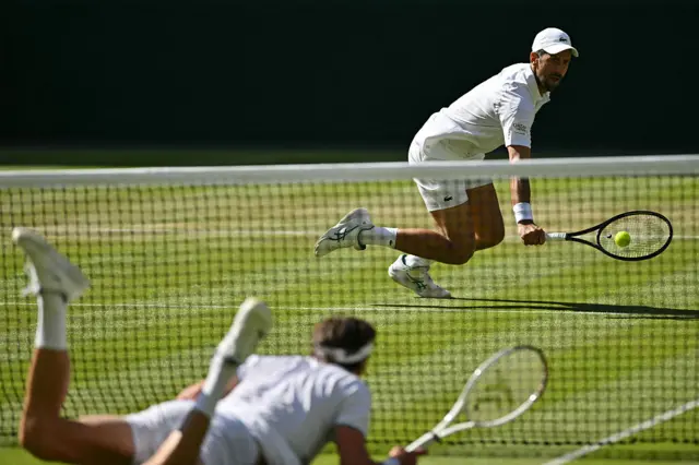 Novak Djokovic and Arthur Rinderknech falling to the floor
