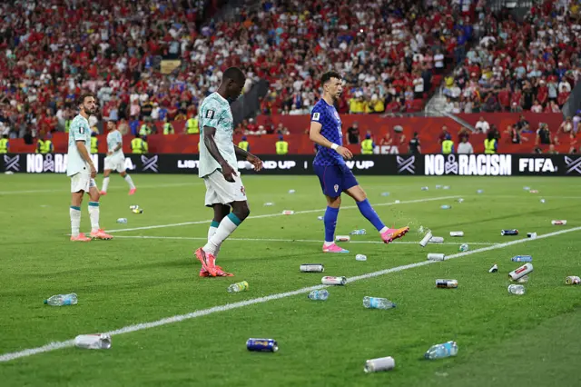 Bottles and cans thrown by fans are seen on the pitch