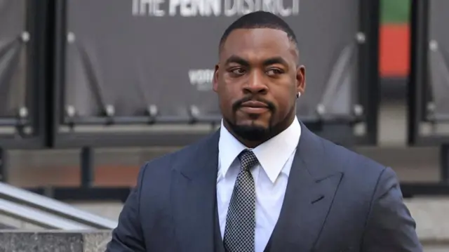 Kansas City Chiefs player Chris Jones arrives at Madison Square Garden wearing a dark suit with a checked tie