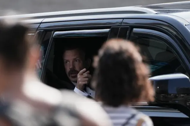 US actor Jason Sudeikis motions from his black SUV as he arrives at Madison Square Garden