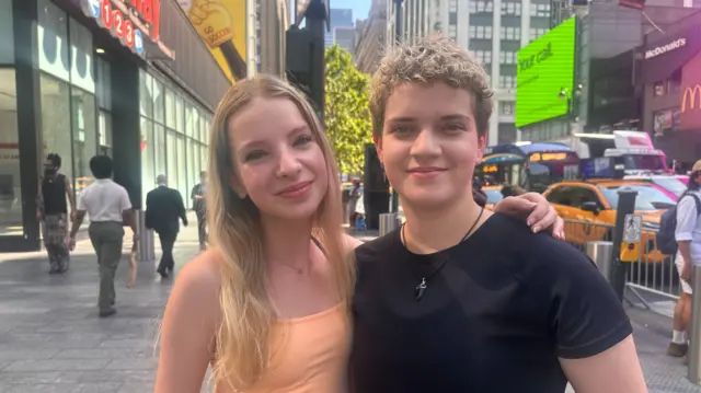 Emily puts her arm around James as they pose for a photo