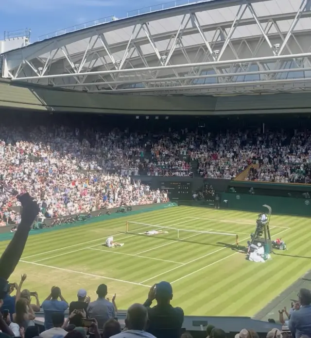 Novak Djokovic and Arthur Rinderknech lie on the ground
