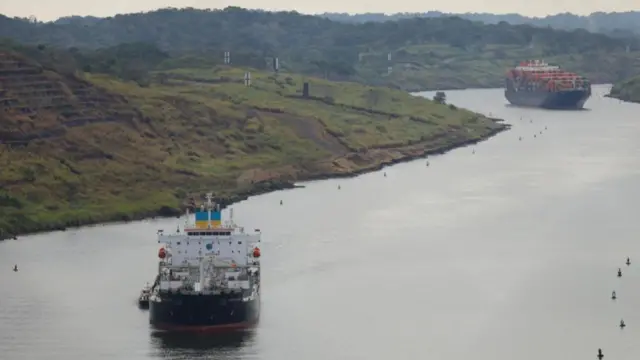 Two shipping containers visible on the Panama Canal in misty weather