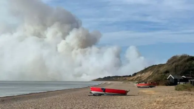 Suffolk shoreline with smoke from Dunwich Heath fire billowing in the distance