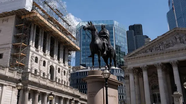 The Bank of England building with the equestrian statue of the Duke of Wellington visible. The sun is shining on the building and statue.