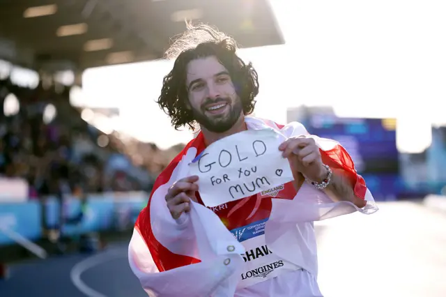 Zac Shaw celebrates gold with a sign that says "gold for you mum"