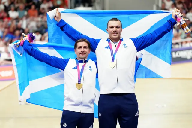 Neil Fachie and Aaron Pope hold up the Saltire on the podium