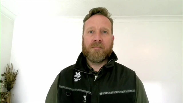 Matt Wilson in a green jumper with a black National Trust branded zip up vest over the top.