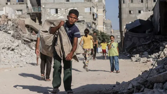A Palestinian boy carrying a bag over his shoulder walks through a heavily damaged street in Khan Yunis in the southern Gaza Strip.