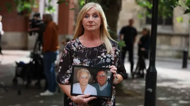 Karen Bush is pictured outside court holding a photograph of her parents.