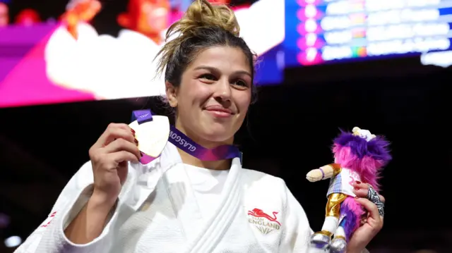 Acelya Toprak holds up her gold medal and mascot while smiling